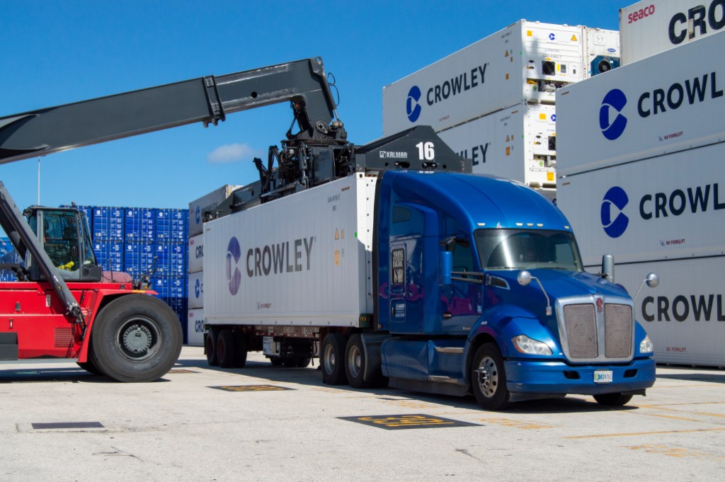 Logística de cadena de frío de Crowley con contenedores refrigerados, camión y grúa reach stacker en operación