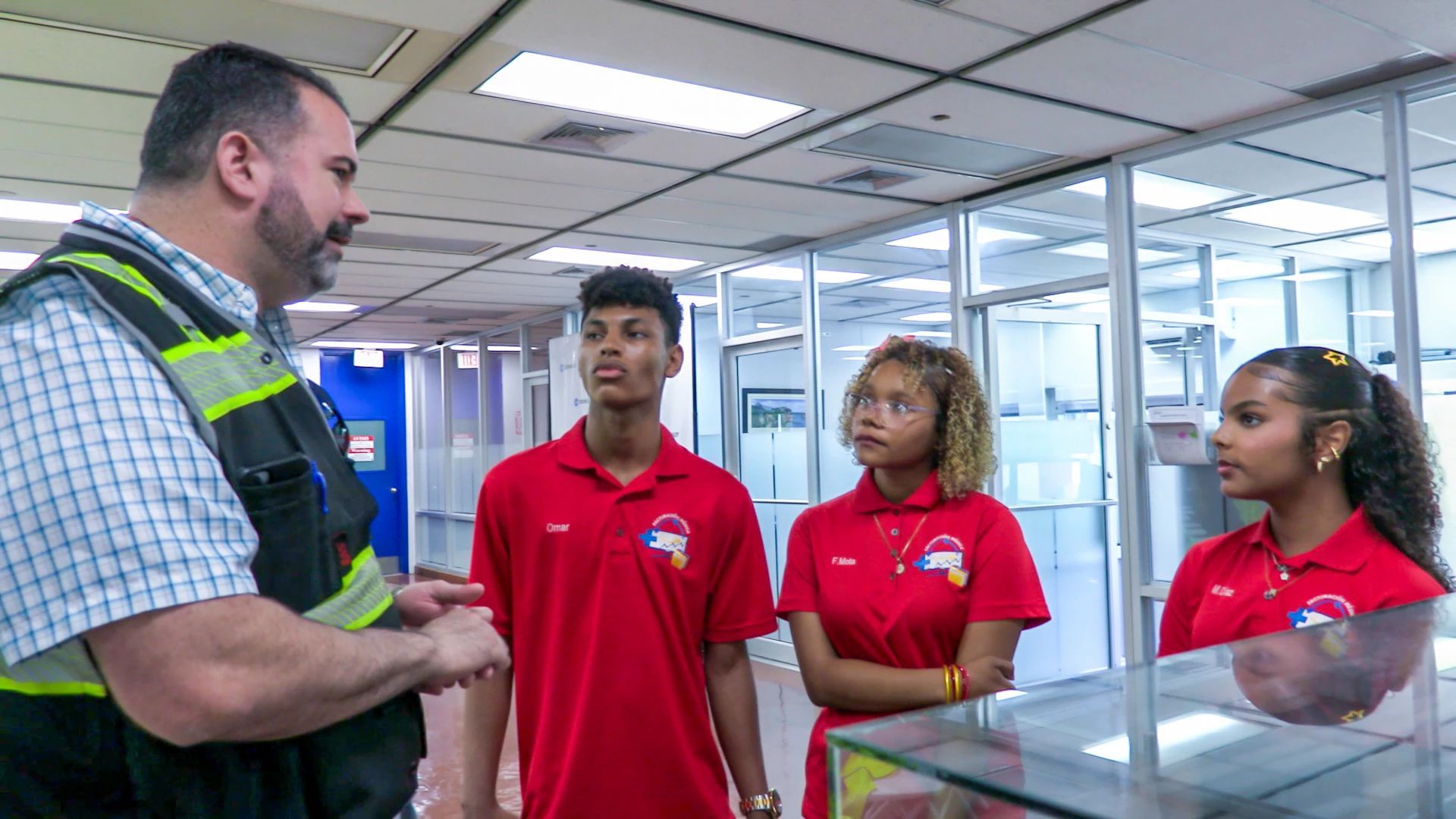 Crowley employee speaks with three students during a workforce development and career exploration visit inside an office facility.