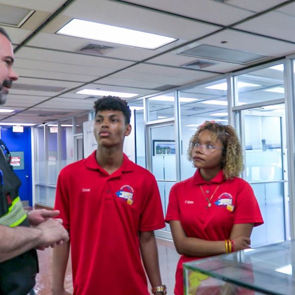 Crowley employee speaks with three students during a workforce development and career exploration visit inside an office facility.